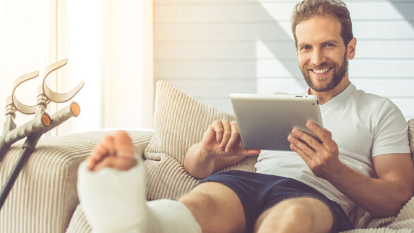 Mann mit Gipsfuß auf Couch